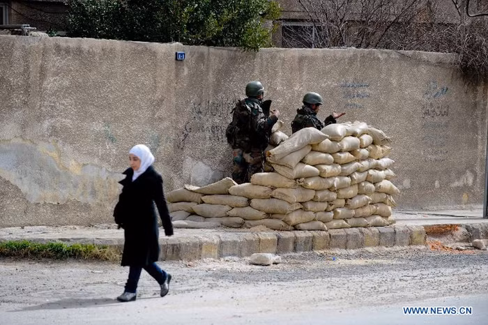 Một người phụ nữ đi qua chốt kiểm soát của quân đội Syria ở Harasta (Ảnh: News.cn) Một người phụ nữ đi qua chốt kiểm soát của quân đội Syria ở Harasta (Ảnh: News.cn)