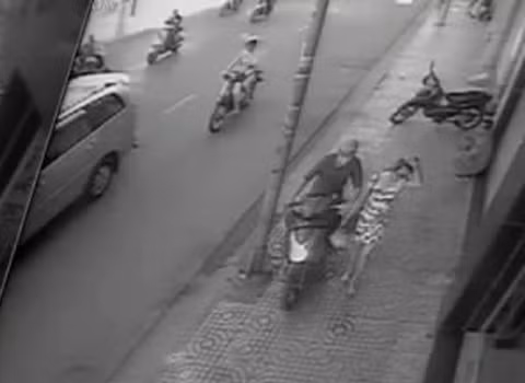 Tên cướp chạy xe máy liều lĩnh leo lên vỉa hè, lách qua cột đèn lao đến bên cô gái.