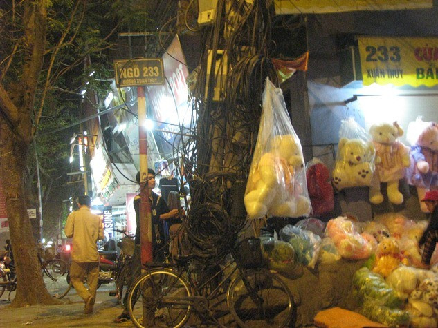 Trên vỉa hè dành cho người đi bộ, những đoạn dây cáp điện chằng chịt tạo thành những mớ bòng bong vô hình được người dân tận dụng treo để bán hàng. Trên vỉa hè dành cho người đi bộ, những đoạn dây cáp điện chằng chịt tạo thành những mớ bòng bong vô hình được người dân tận dụng treo để bán hàng.
