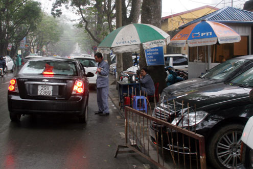 Hết chỗ trên vỉa hè, nhân viên Công ty Khai thác điểm đỗ còn bố trí cho khách đỗ ô tô dưới lòng đường