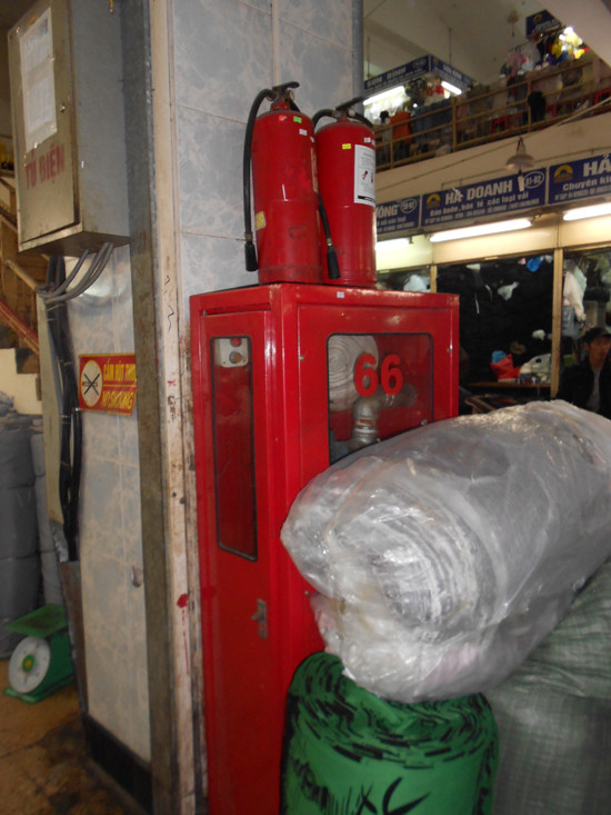 Thông thường, để đảm bảo an toàn, các thiết bị phòng cháy chữa cháy thường được đặt cách xa các tủ điện, thiết bị điện một đoạn để nếu có xảy ra sự cố chập, cháy điện thì có thể dễ dàng dập lửa từ xa nhưng tại một số chợ, kiểu lắp đặt ngay sát tủ điện và bị hàng hóa che lấp như thế này, khi xảy ra hỏa hoạn người cứu hỏa nếu không chết vì bị lửa cháy thì cũng chết vì...điện giật.