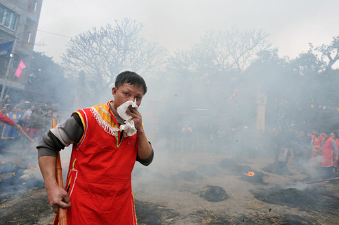 Một thí sinh vừa xử lý niêu cơm vừa dùng khăn lau mũi vì ngạt khói. Một thí sinh vừa xử lý niêu cơm vừa dùng khăn lau mũi vì ngạt khói.