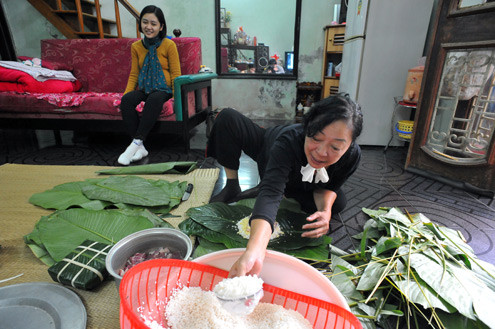 rong khi bà ngồi gói, cô con gái đang mang bầu không thể giúp gì được mẹ đành ngồi xem phía sau. rong khi bà ngồi gói, cô con gái đang mang bầu không thể giúp gì được mẹ đành ngồi xem phía sau.