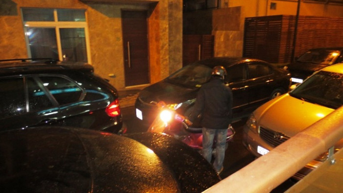 Một chiếc xe máy bị mắc kẹt giữa dàn ô tô, không biết đi lối nào.