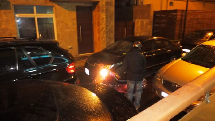 Một chiếc xe máy bị mắc kẹt giữa dàn ô tô, không biết đi lối nào.