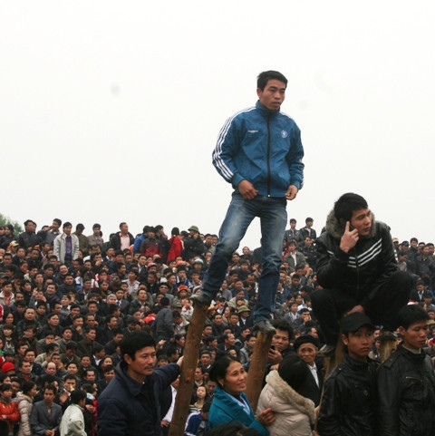 Một thanh niên đứng hẳn lên hai thanh gỗ để có thể xem được