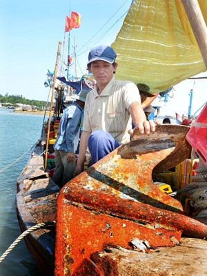 Chủ tàu Trần Văn Quang và chiếc mỏ neo bị tàu Trung Quốc đâm lút vào mũi tàu. Ảnh: Đức Nguyễn.