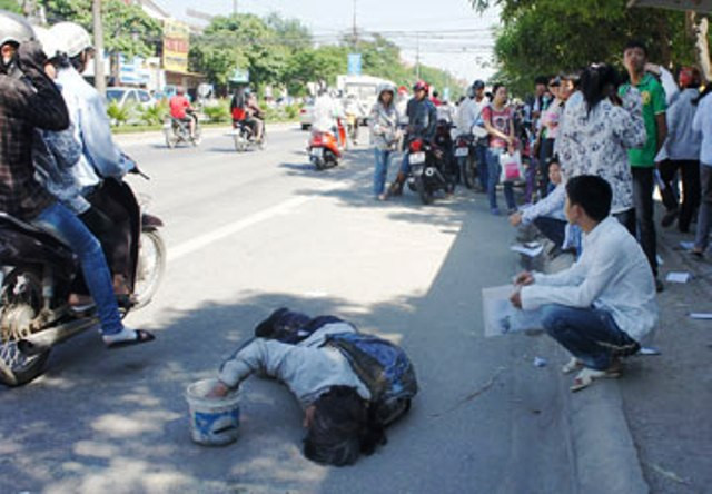 Một đứa bé nằm khóc vật vã xin tiền trước cổng Trường ĐH Vinh để xin tiền. (Ảnh: Đ. Lam)