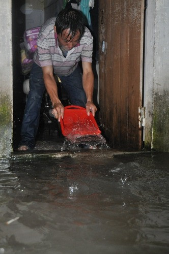 Đến 18h chiều nay, khu vực này vẫn ngập trong nước. Ảnh: Dùng mọi dụng cụ trong nhà để tát nước.