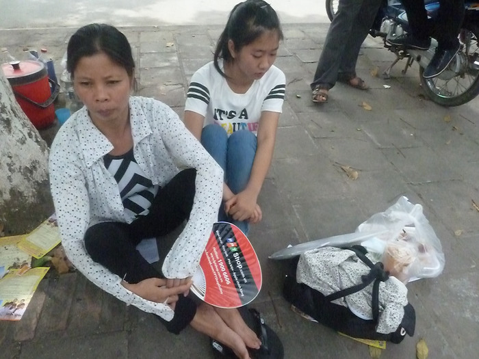 Hai mẹ con ngồi tranh thủ nghỉ ngơi trước khi đi về