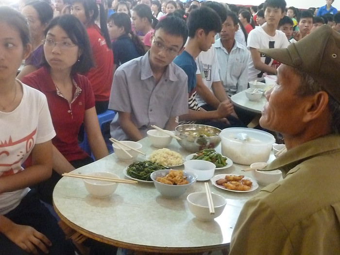 Sĩ tử và người nhà chăm chú lắng nghe lời sư chủ trì trước bữa cơm Sĩ tử và người nhà chăm chú lắng nghe lời sư chủ trì trước bữa cơm