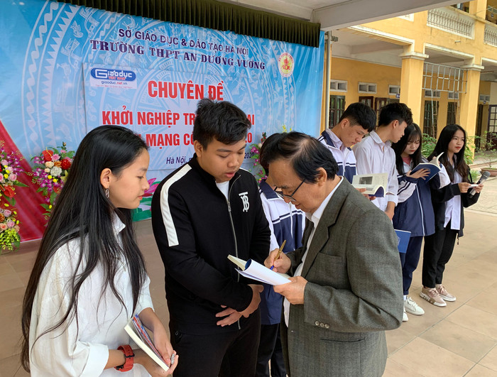 Giáo sư Nguyễn Lân Dũng tặng sách cho đại diện các em học sinh Trường Trung học phổ thông An Dương Vương. Ảnh: Tùng Dương.