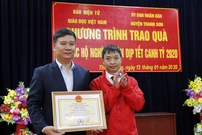 Nhà báo Nguyễn Tiến Bình - Tổng biên tập Báo điện tử Giáo dục Việt Nam (người bên trái ) đang nhận bảng nghi nhận của Hội chữ thập đỏ huyện Thanh Sơn về công tác tặng quà Tết cho người nghèo của huyện. Ảnh: Tùng Dương.