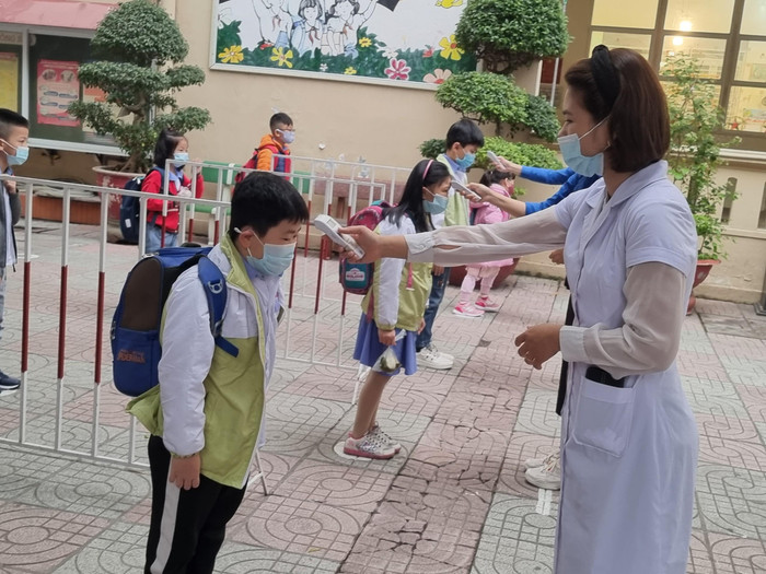 Học sinh Trường Tiểu học Đinh Tiên Hoàng được đo thân nhiệt trước khi vào lớp (Ảnh: Phương Linh)