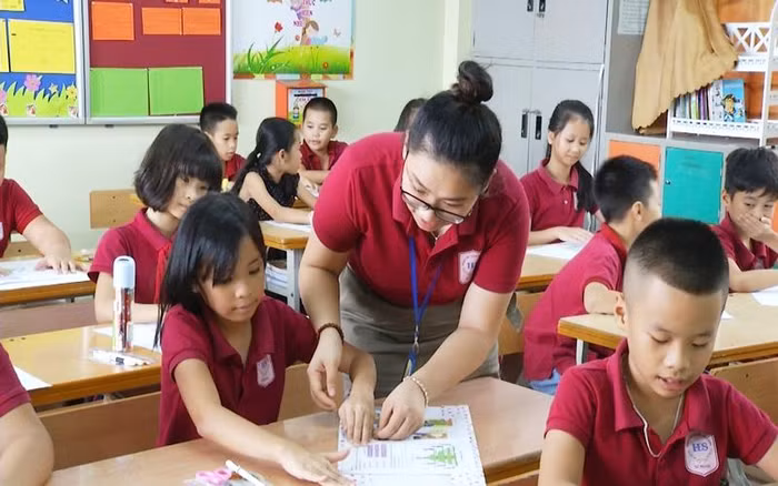 Giáo viên Trường Tiểu học Đoàn Thị Điểm hướng dẫn học sinh bọc vở bằng giấy gói quà (Ảnh: Hằng Ngần)