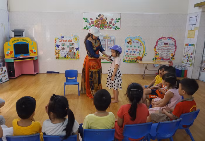 Cô giáo Phạm Thị Lý hướng dẫn học sinh đội mũ bảo hiểm đúng cách (Ảnh: Lã Tiến)