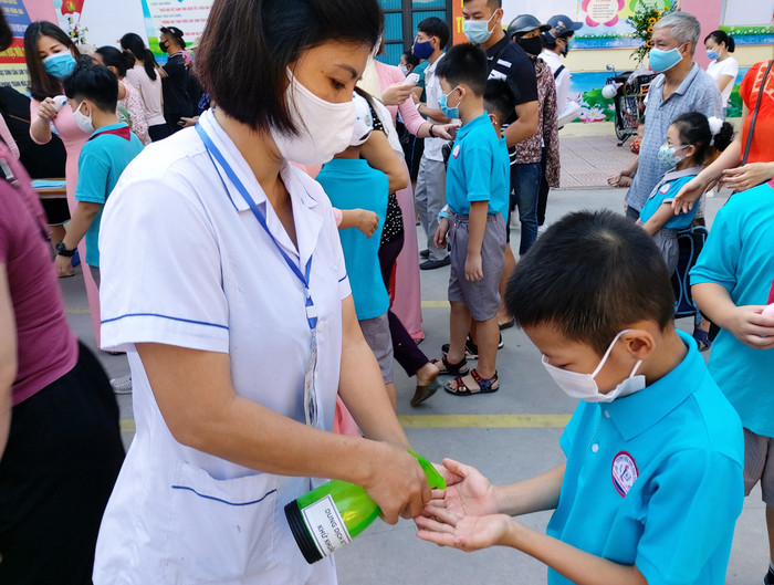 Học sinh được khử khuẩn tay trước cổng trường (Ảnh: Lã Tiến)