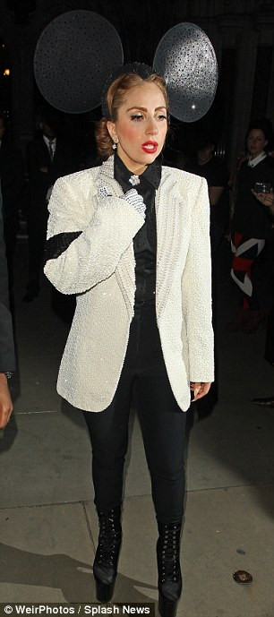 Sau khi rời buổi trình diễn trên, Lady Gaga đã có vẻ ăn mặc bình thường trở lại trong trang phục tuxedo màu kem đính những hạt pha lê lấp lánh của NTK Swarovski và chiếc quần tất đen, nhưng lại gắn thêm một cặp tai chú chuột Mickey khổng lồ trên đầu. Ảnh. Splash.