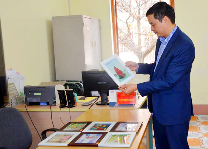 Thầy giáo Hiếu giới thiệu những sản phẩm tranh giấy do các học sinh khiếm thính làm. (Ảnh: Cộng tác viên)