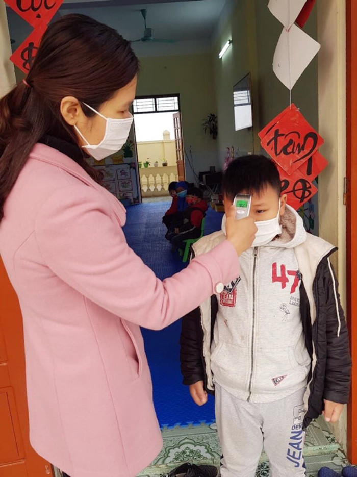 Học sinh được giáo viên đo nhiệt độ cơ thể trước khi vào lớp (Ảnh: CTV)