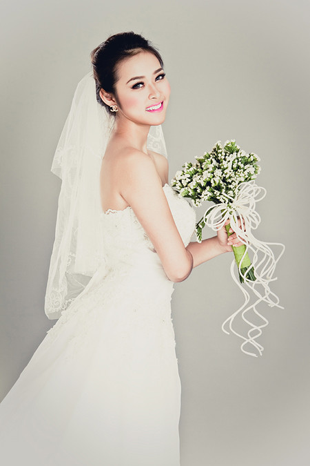 Style váy cưới Diệp Bảo Ngọc diện cũng chính là xu hướng được nhiều bạn trẻ ưa chuộng hiện nay. Thay vì cài hoa, tóc được vấn tròn nhẹ, điểm xuyến khăn voan trắng thanh lịch. Gương mặt được make up khá đậm, sắc môi tươi tắn, làm nổi bật vẻ đẹp thanh tân thiếu nữ. Theo bạn, hot girl nào là đệ nhất tân nương?
