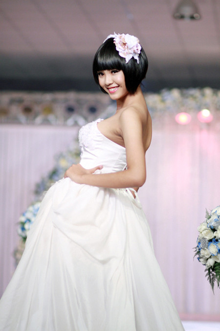 Chân dài Bảo Trân tươi tắn, trẻ trung trên sàn diễn với váy cưới bồng lộng lẫy. Mái tóc ngắn cá tính chỉ điểm xuyết duy nhất bông hoa mẫu đơn tím, vậy mà mang lại hiệu quả thẩm mỹ tuyệt vời.