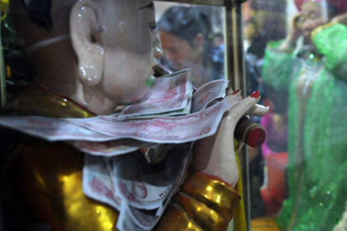 Nhét tiền lẻ vào tủ để tượng tại các chùa. Ảnh: A.T. Nhét tiền lẻ vào tủ để tượng tại các chùa. Ảnh: A.T.