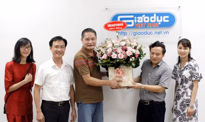 Ông Đào Ngọc Tước, Phó Tổng biên tập Báo Điện tử Giáo dục Việt Nam nhận lẵng hoa chúc mừng từ Phó Giáo sư Đặng Xuân Thư (người thứ 2 từ bên phải vào), Bí thư chi bộ, Phó Hiệu trưởng Trường Đại học Sư phạm Hà Nội 1. Ảnh: Trinh Phúc.