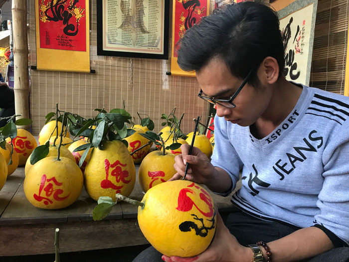 Anh Đỗ Duy Đợi, câu lạc bộ Thư pháp Unesco Việt đang viết chữ lên nhưng trái bưởi. Ảnh: Tùng Dương.