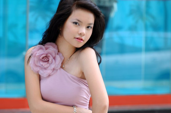 Chiếc đầm tím rất hợp với Thu Trang. Bông hoa tết nằm ngoan xinh trên bờ vai thon tượng trưng cho vẻ đẹp đang độ rực rỡ của thiếu nữ, màu tím nhẹ nhàng tượng trưng nét tính cách bí ẩn, áo vắt chéo vai tượng trưng cho xu hướng thời trang hiện đại.