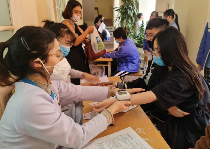 Học sinh nhà trường được chia ca tiêm theo từng lớp. Sau khi hoàn thành các bước khám sàng lọc, tiêm, học sinh được phát sữa, bánh để tăng cường sức khoẻ và được theo dõi 30 phút. Phụ huynh học sinh, giáo viên và đoàn thanh niên của trường động viên, hỗ trợ học sinh tại khu vực theo dõi sau tiêm (Ảnh: Lã Tiến)