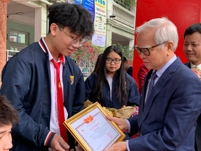 Tiến sĩ Nguyễn Văn Hòa - Chủ tịch Hội đồng quản trị Trường Trung học phổ thông Nguyễn Bỉnh Khiêm trao giấy khen cho em Đỗ Ngọc Thành dũng cảm tham gia bắt cướp. Ảnh: Tùng Dương.