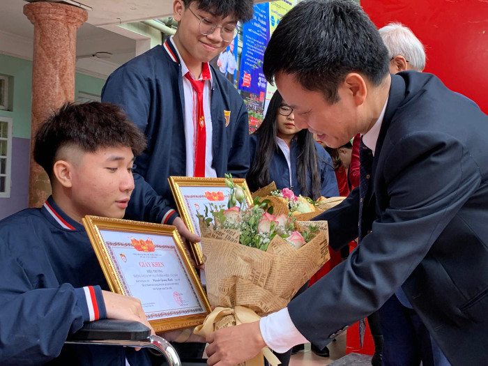 Thầy Đàm Tiến Nam - Hiệu trưởng Trường Trung học phổ thông Nguyễn Bỉnh Khiêm tặng hoa cho em Nguyễn Quang Mạnh. Ảnh: Tùng Dương.