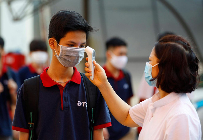 Học sinh Trường Trung học phổ thông Đoàn Thị Điểm, Hà Nội được đo thân nhiệt trước khi lên xe ô tô đưa đón đến trường. Ảnh: Tùng Dương.