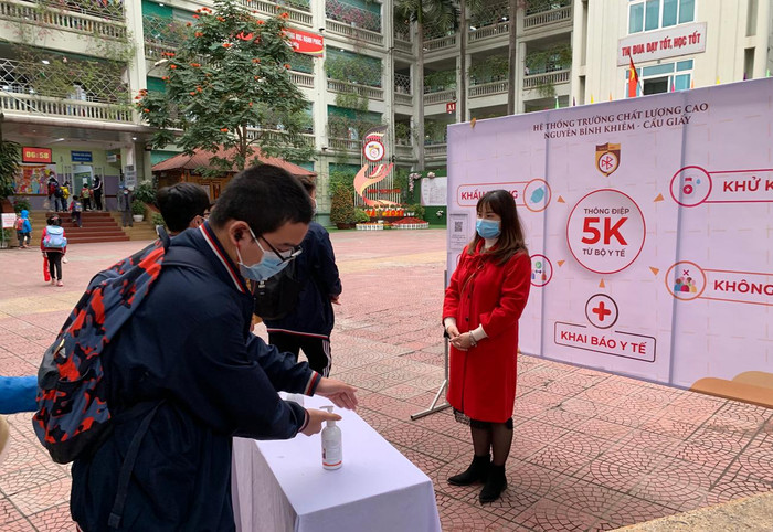 Học sinh Trường Trung học cơ sở và Trung học phổ thông Nguyễn Bỉnh Khiêm, Cầu Giấy, Hà Nội trước khi vào trường đều được nhắc nhở sát khuẩn tay phòng dịch. Ảnh: Tùng Dương.