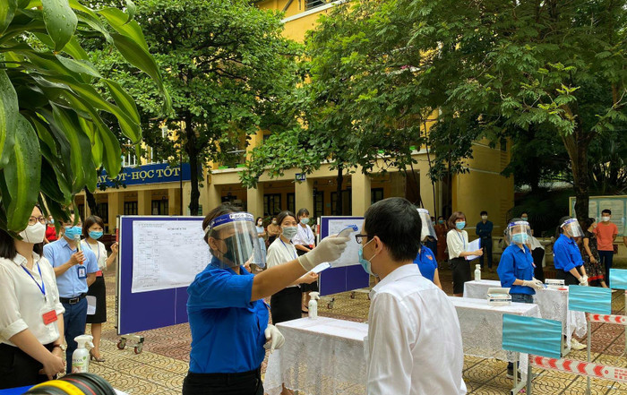 Đảm bảo giãn cách 2m/1 người và đo nhiệt độ, khử khuẩn trước khi vào làm thủ tục thi. Ảnh: T.D.