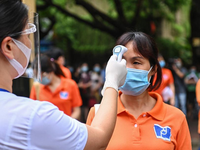 Các nhân viên y tế đo thân nhiệt, sát khuẩn cho thí sinh trước khi vào làm thủ tục, ngoài ra còn có 2 giáo viên hỗ trợ khi cần thiết. Ảnh: G.H.