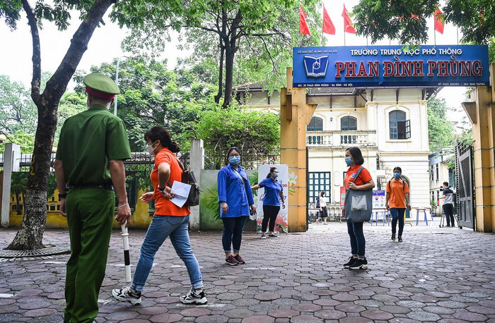 Phía ngoài cổng điểm thi, các lực lượng hướng dẫn thi sinh ra về đảm bảo khoảng cách, không tụ tập đông người. Ảnh: G.H.