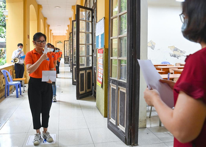 Tất cả các thí sinh trước khi vào phòng thi phải đứng theo vị trí đã được đánh dấu trên sàn nhà, cách nhau 2 m, được yêu cầu mở khẩu trang để giám thị nhận dạng. Ảnh: G.H.