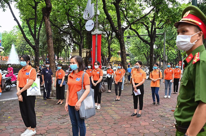 Lực lượng công an, tình nguyện viên hướng dẫn, giám sát thí sinh đến dự thi đứng giãn cách 2 m để đảm bảo an toàn phòng chống dịch. Ảnh: G.H.
