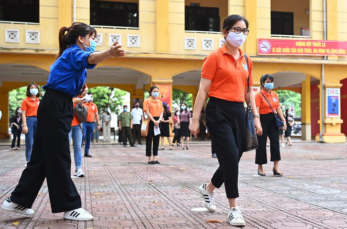 Tình nguyện viên trực sắn tại các điểm thi để hướng dẫn thí sinh đi theo đúng đường đã được quy định trước khi làm thủ tục vào phòng thi. Ảnh: G.H.