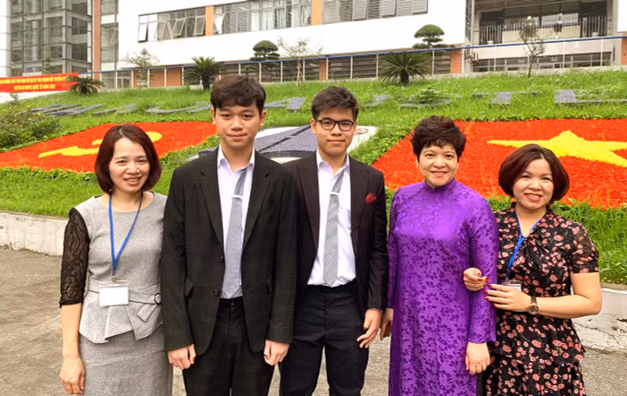 Hai bạn học sinh Đỗ Gia Khánh (bên trái ảnh) và Ngô Gia Bảo chụp ảnh lưu niệm với nhà giáo Trần Thùy Dương - Hiệu trưởng Trường Trung học phổ thông chuyên Hà Nội - Amsterdam cùng phụ huynh của hai em. Ảnh: Tùng Dương.