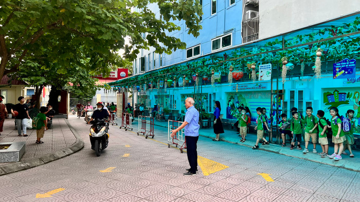 Bảo vệ nhà trường hướng dẫn phụ huynh vào vị trí chờ đón học sinh (Ảnh: LH)