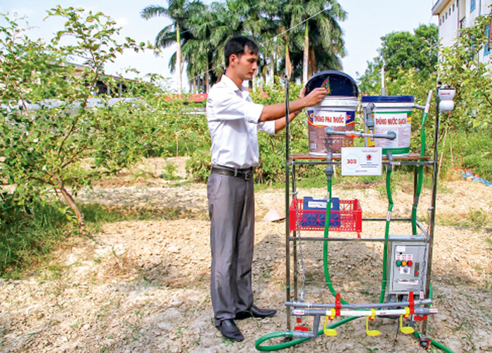 Thầy giáo Nguyễn Xuân Huỳnh với thiết bị cho gà uống thuốc tự động (Ảnh: CTV) Thầy giáo Nguyễn Xuân Huỳnh với thiết bị cho gà uống thuốc tự động (Ảnh: CTV)
