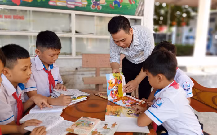 Thầy giáo Nguyễn Văn Bình hướng dẫn các em học sinh lựa chọn, đọc sách (Ảnh: Lã Tiến)