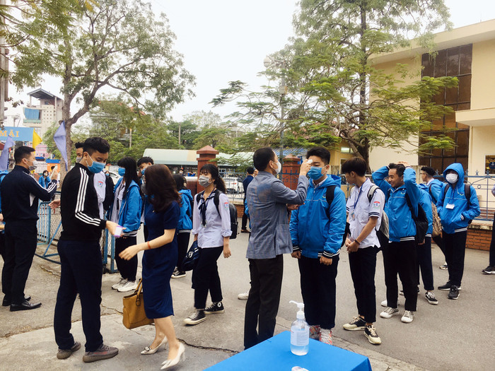 Giáo viên Trường Trung học phổ thông Hàng Hải kiểm tra thân nhiệt học sinh ngay tại cổng trường. (Ảnh: Lã Tiến) Giáo viên Trường Trung học phổ thông Hàng Hải kiểm tra thân nhiệt học sinh ngay tại cổng trường. (Ảnh: Lã Tiến)