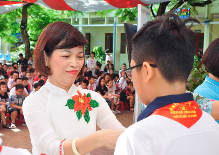 Cô giáo Lê Thị Minh Tâm, Hiệu trưởng Trường Trung học cơ sở Tô Hiệu trao khăn quàng tiếp lửa cho học sinh khối 6 (Ảnh: Quyết Cương)