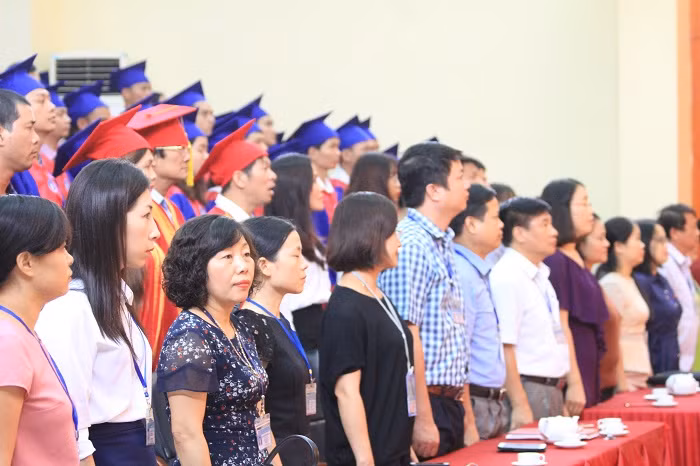 Lãnh đạo nhà trường cùng các tân thạc sĩ, tiến sĩ làm lễ chào cờ. Ảnh của Xuân Quang.