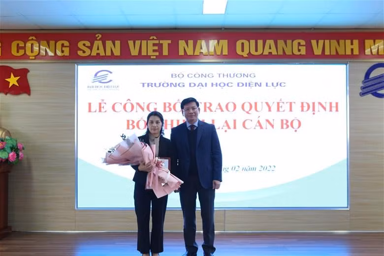 Phó giáo sư - Tiến sĩ Đinh Văn Châu trao quyết định và hoa cho viên chức được bổ nhiệm lại.