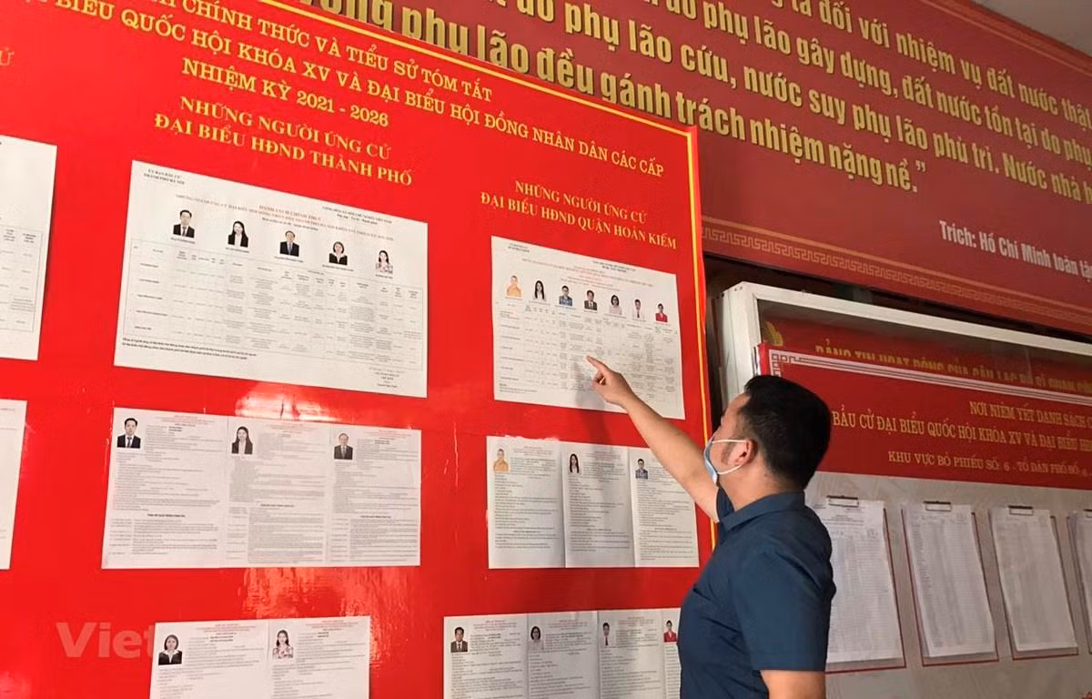Cử tri xem xét danh sách niêm yết những người ứng cử đại Quốc hội khóa XV và Hội đồng Nhân dân các cấp nhiệm kỳ 2021-2026. (Ảnh: Xuân Quảng/Vietnam+)